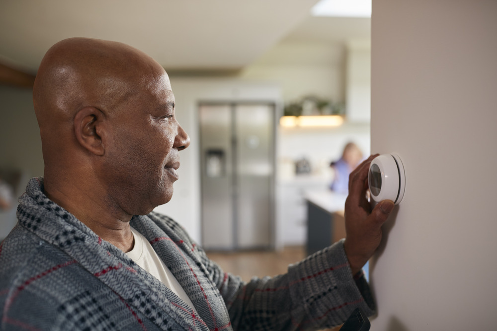 Man Turning On Heater Man adjusting thermostat to increase heat inside his home